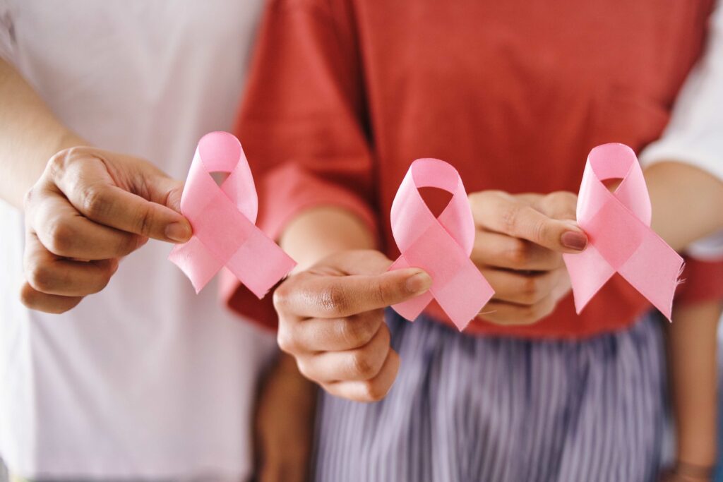 Tr&ecirc;s m&atilde;os femininas segurando la&ccedil;os s&iacute;mbolos do outubro rosa